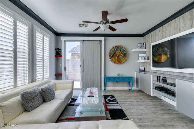 living room with a ceiling fan, wood finished floors, visible vents, and ornamental molding