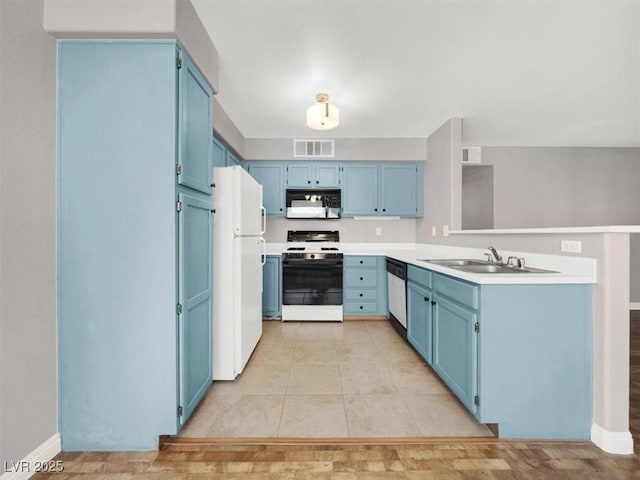 kitchen with white appliances, visible vents, blue cabinets, light countertops, and a sink