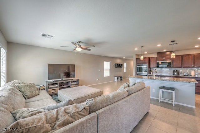 tiled living room with ceiling fan and sink