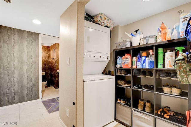 washroom with stacked washer and dryer and light tile patterned floors