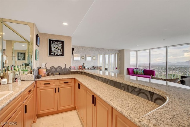 kitchen with a wealth of natural light, light stone counters, light brown cabinetry, and light tile patterned floors