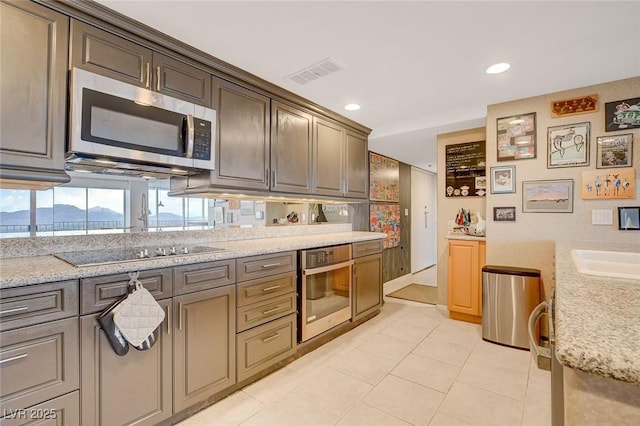 kitchen featuring light tile patterned flooring, sink, tasteful backsplash, stainless steel appliances, and light stone countertops