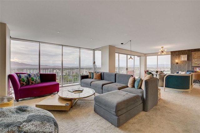 living room with floor to ceiling windows, a mountain view, light colored carpet, and wood walls