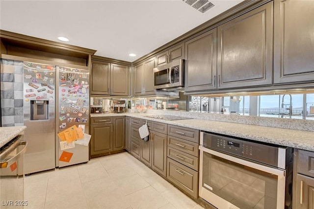 kitchen featuring appliances with stainless steel finishes, light stone countertops, and light tile patterned floors