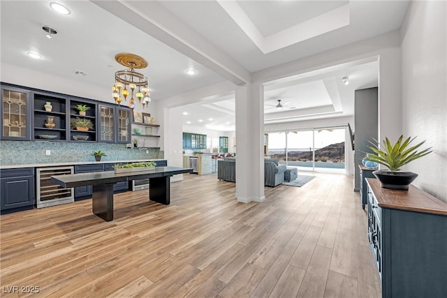 bar featuring backsplash, beverage cooler, light wood-type flooring, and a tray ceiling