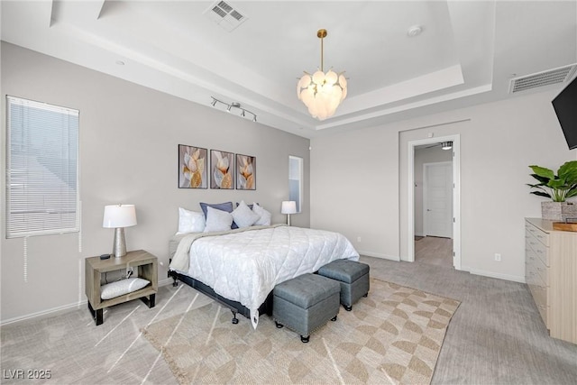 carpeted bedroom with a raised ceiling and an inviting chandelier