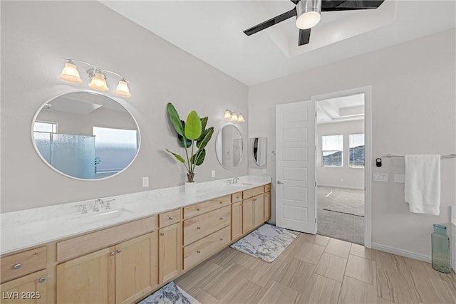 bathroom with ceiling fan, vanity, and a raised ceiling