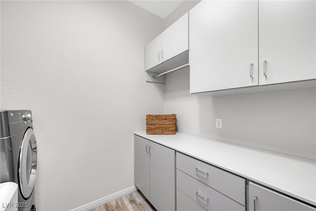 washroom featuring washer / clothes dryer, light hardwood / wood-style flooring, and cabinets