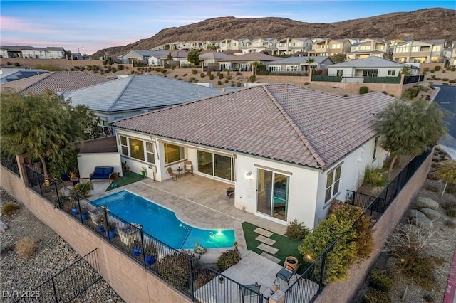 back house at dusk with a fenced in pool, a patio, and a mountain view