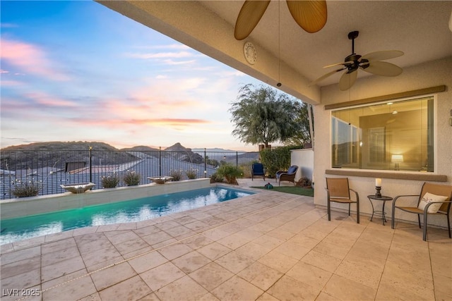 pool at dusk with a mountain view and a patio area