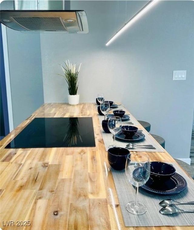 kitchen with black electric cooktop, wood finished floors, and exhaust hood