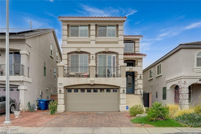 view of front of house with decorative driveway, a tile roof, an attached garage, and stucco siding