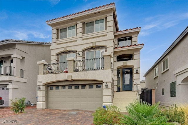 mediterranean / spanish home featuring stucco siding, an attached garage, a tile roof, and decorative driveway