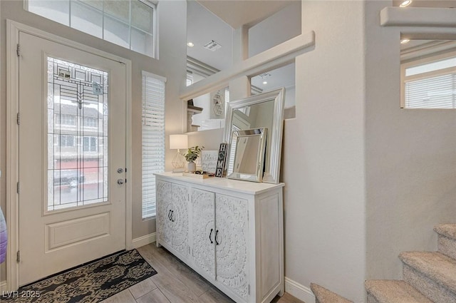 foyer with stairway, visible vents, light wood-type flooring, and baseboards