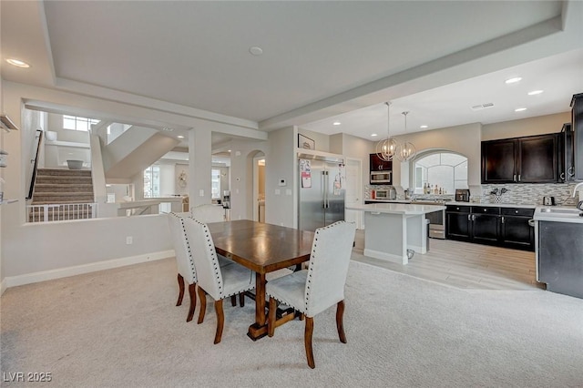 dining area with light carpet, a notable chandelier, recessed lighting, arched walkways, and baseboards