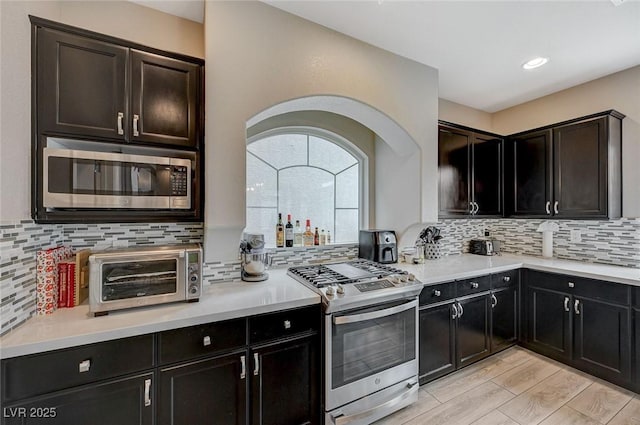 kitchen with a toaster, backsplash, stainless steel appliances, and light wood-type flooring