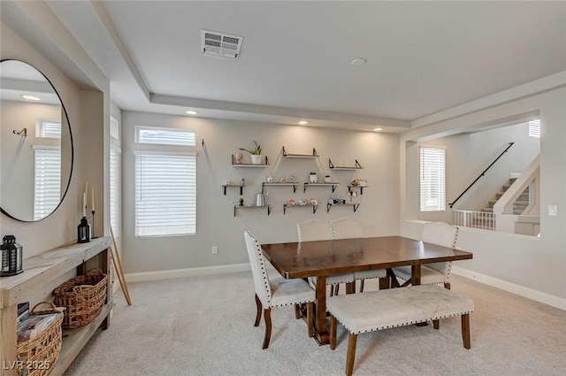 dining room with light carpet, visible vents, plenty of natural light, and baseboards