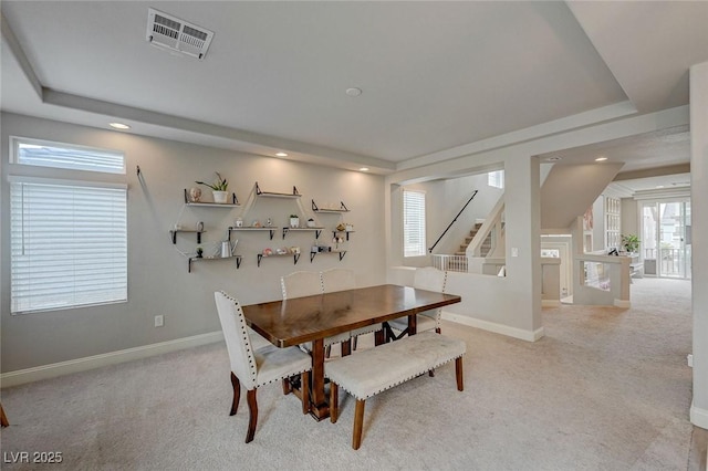 carpeted dining room featuring stairs, a tray ceiling, baseboards, and visible vents