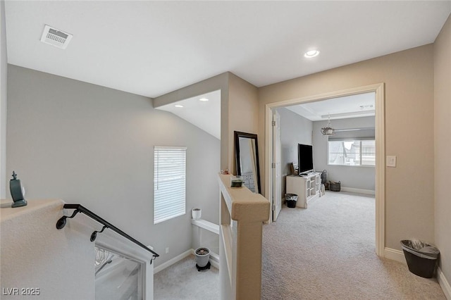 hall with visible vents, carpet floors, baseboards, and an upstairs landing