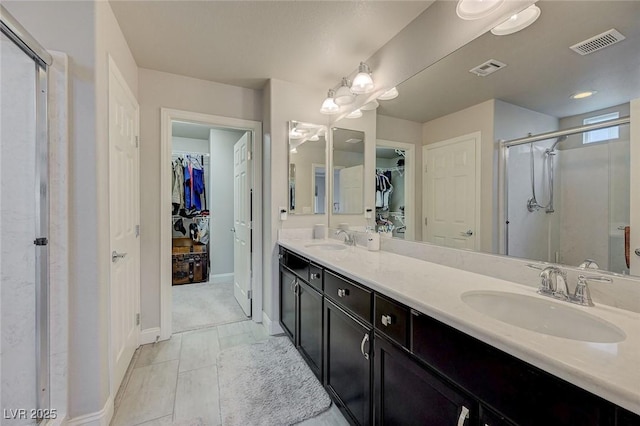 bathroom featuring double vanity, a stall shower, visible vents, and a sink