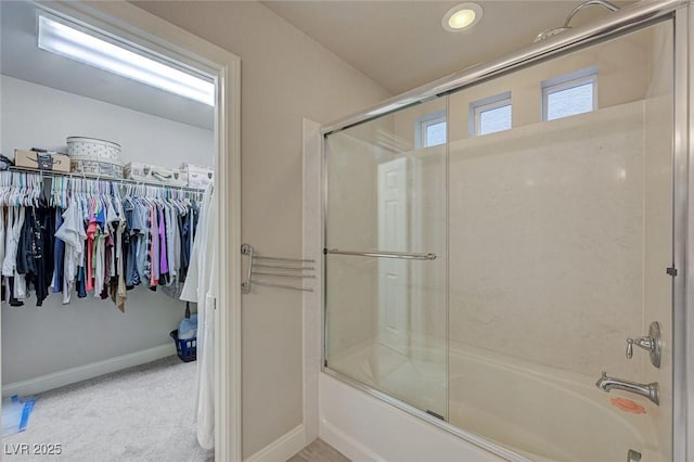 bathroom with baseboards, enclosed tub / shower combo, and a spacious closet