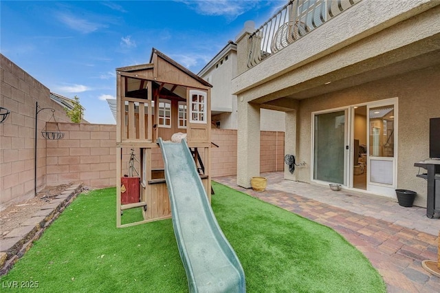 view of jungle gym featuring a yard, a patio area, and a fenced backyard