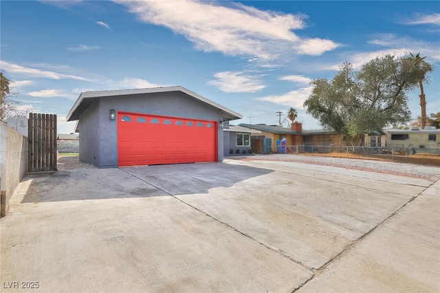 view of front of home featuring a garage, driveway, fence, and stucco siding