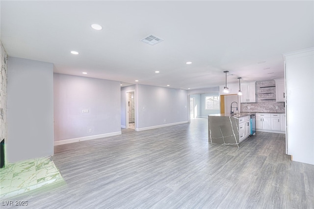 unfurnished living room featuring recessed lighting, a sink, visible vents, baseboards, and light wood-type flooring