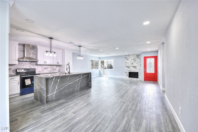 kitchen with wood finished floors, white cabinets, electric range oven, wall chimney exhaust hood, and tasteful backsplash