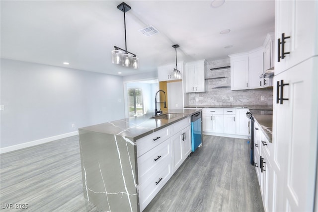 kitchen featuring dark countertops, visible vents, decorative backsplash, appliances with stainless steel finishes, and a sink