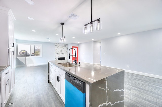 kitchen with visible vents, dishwashing machine, open floor plan, a kitchen island with sink, and a sink