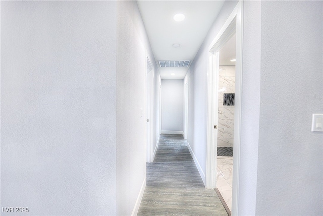 hallway featuring wood finished floors, visible vents, and baseboards