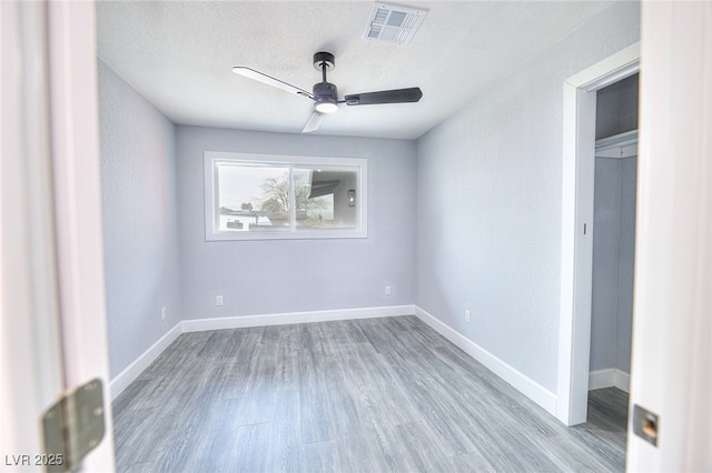 unfurnished bedroom with baseboards, a textured ceiling, visible vents, and wood finished floors