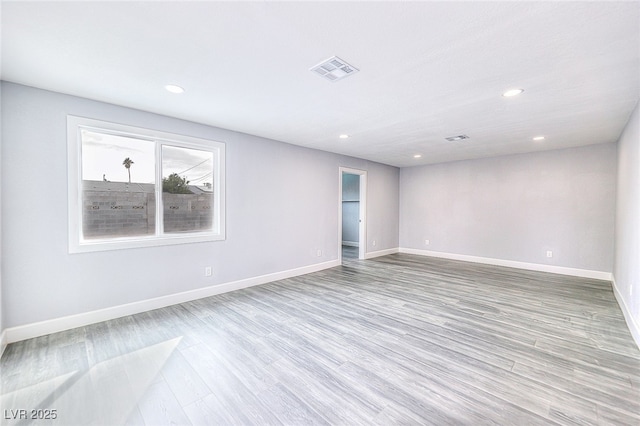 unfurnished room with recessed lighting, wood finished floors, visible vents, and baseboards