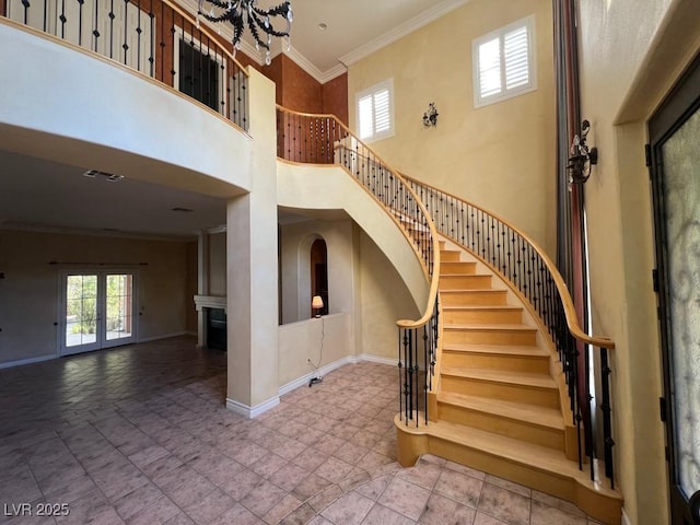 stairs with a towering ceiling, ornamental molding, french doors, and a chandelier