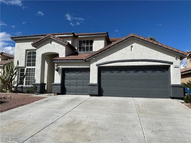 mediterranean / spanish home featuring concrete driveway, a garage, and stucco siding