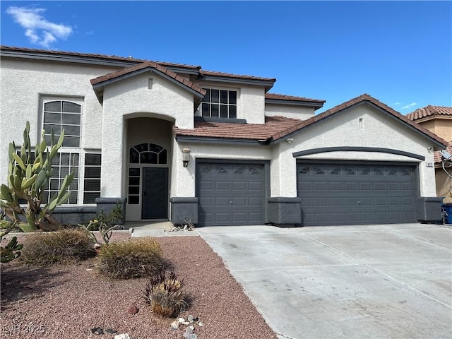 view of front of property with a tile roof, an attached garage, driveway, and stucco siding