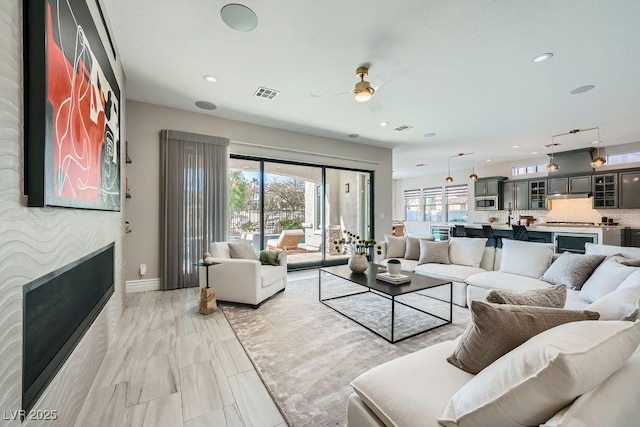 living room featuring a healthy amount of sunlight, a large fireplace, and ceiling fan