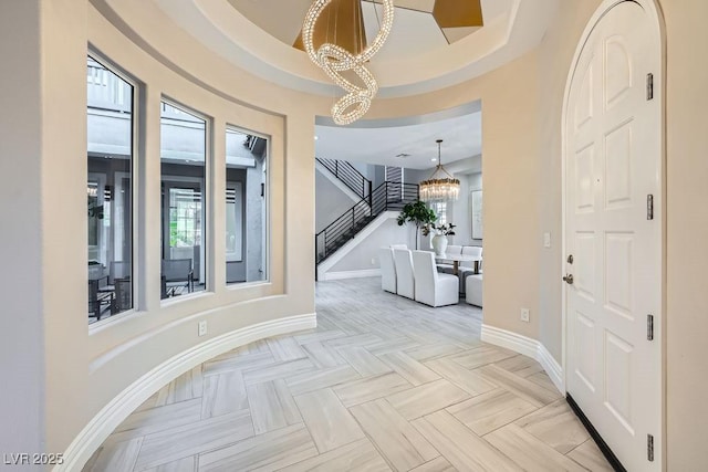 foyer entrance featuring a healthy amount of sunlight, light parquet flooring, and a chandelier