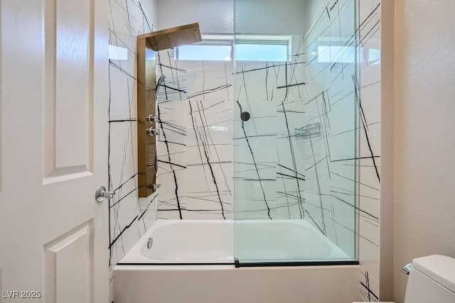 bathroom featuring toilet and shower / bath combination with glass door