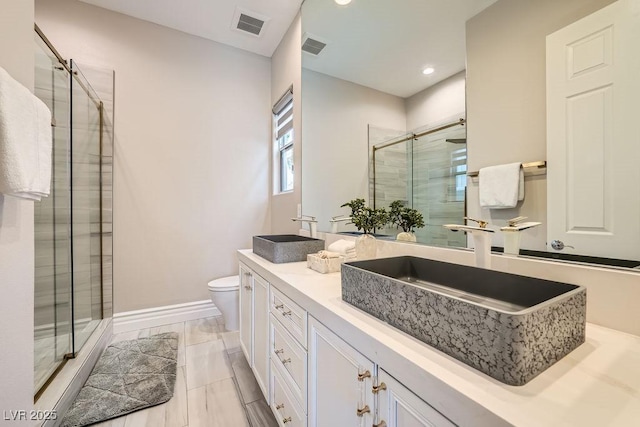 bathroom featuring vanity, toilet, and a shower with shower door