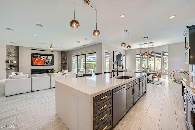 kitchen with sink, appliances with stainless steel finishes, a kitchen island with sink, plenty of natural light, and decorative light fixtures