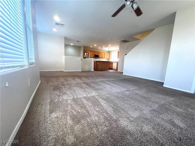 unfurnished living room featuring ceiling fan, carpet, visible vents, and baseboards