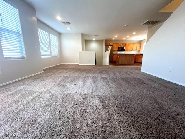 unfurnished living room with recessed lighting, carpet flooring, visible vents, and baseboards