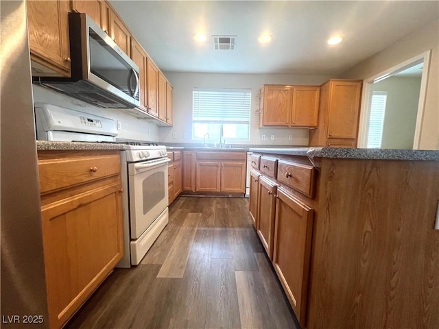 kitchen with dark wood finished floors, white gas stove, recessed lighting, stainless steel microwave, and visible vents