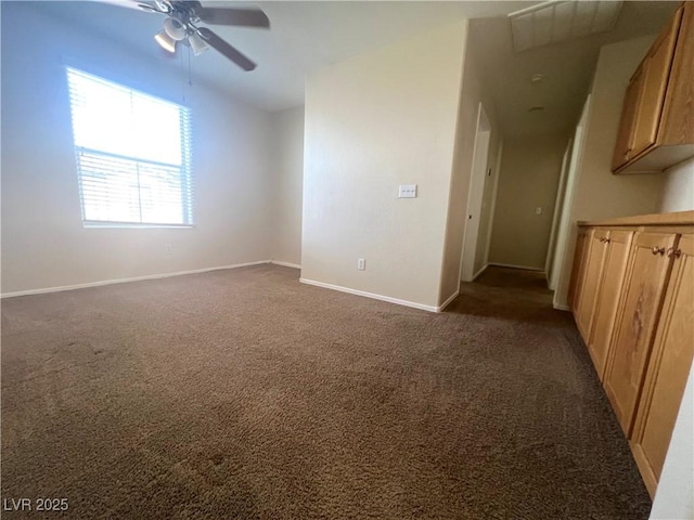 spare room featuring dark carpet, a ceiling fan, and baseboards