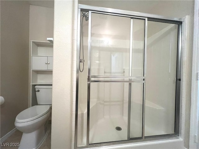 bathroom featuring toilet, a stall shower, and baseboards