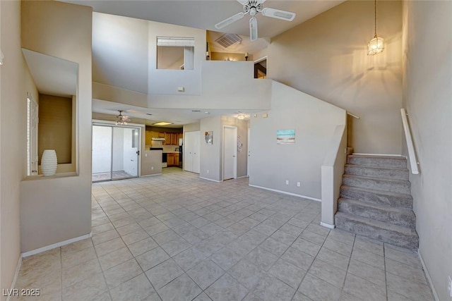 unfurnished living room featuring a towering ceiling, light tile patterned floors, and ceiling fan