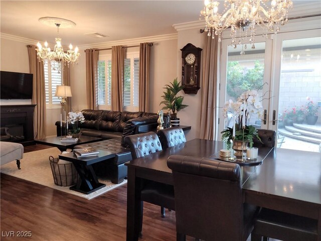 dining space with a chandelier, a wealth of natural light, crown molding, and wood finished floors