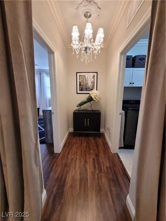 hallway featuring dark wood finished floors, crown molding, baseboards, and an inviting chandelier